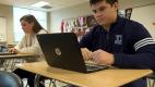 a person sitting at a table using a laptop computer