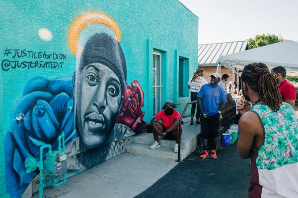 Giovannie Dixon, an artist, stands back to look at a mural he created to memorialize Dion Johnson, a black man who was killed by Arizona state troopers while he was sleeping in his car.