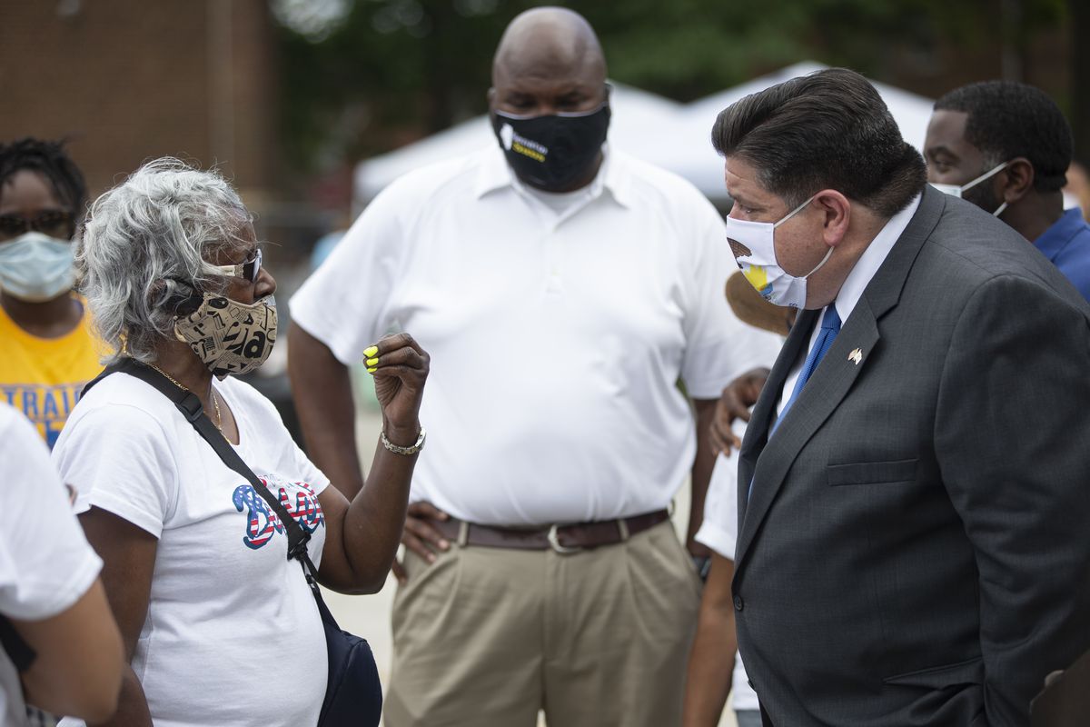 Gov. J.B. Pritzker speaks to a community resident during a visit to a mobile COVID-19 testing station at Edward Coles School on Wednesday.