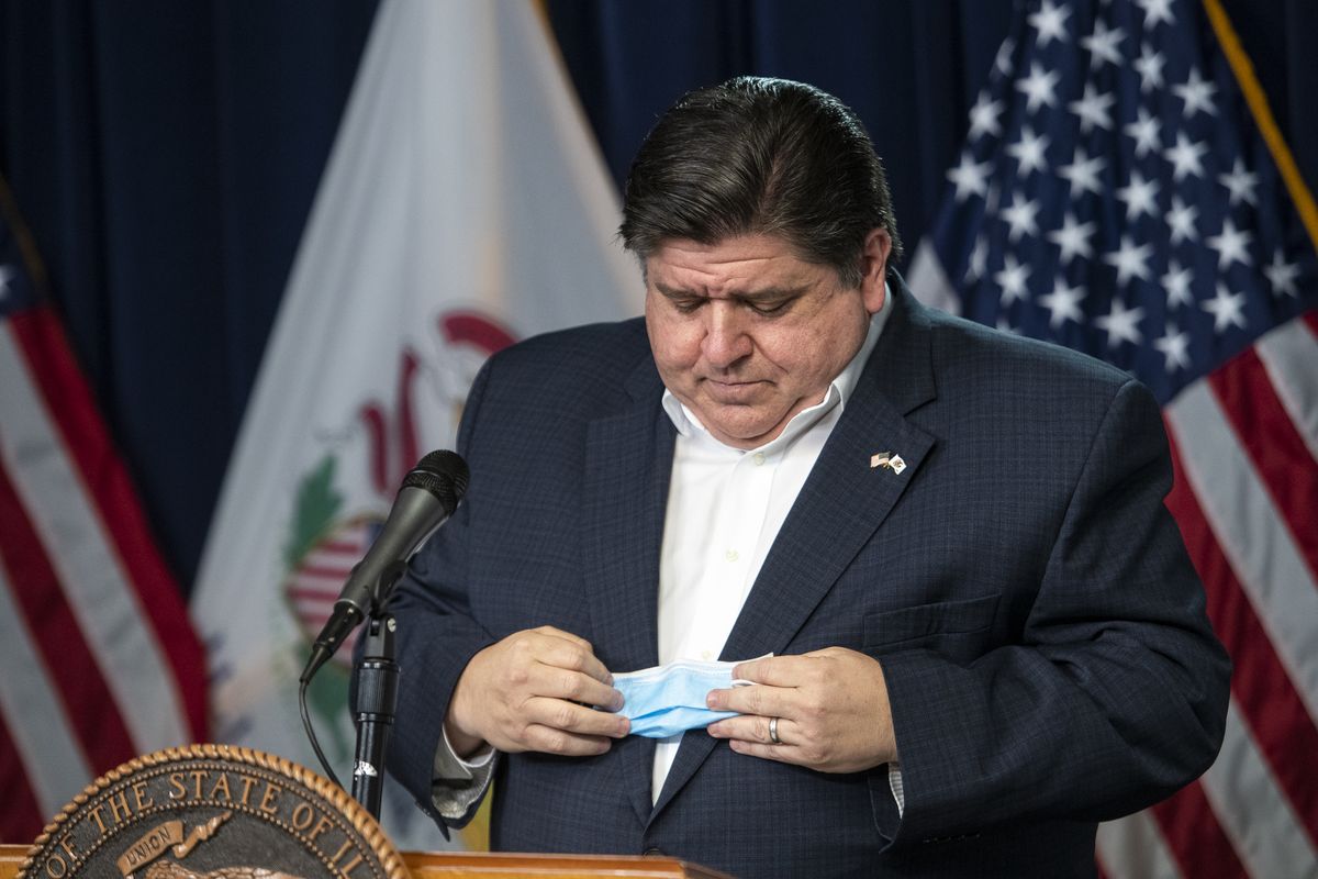 Gov. J.B. Pritzker puts away his face mask before delivering his daily Illinois coronavirus update at the Thompson Center in April.
