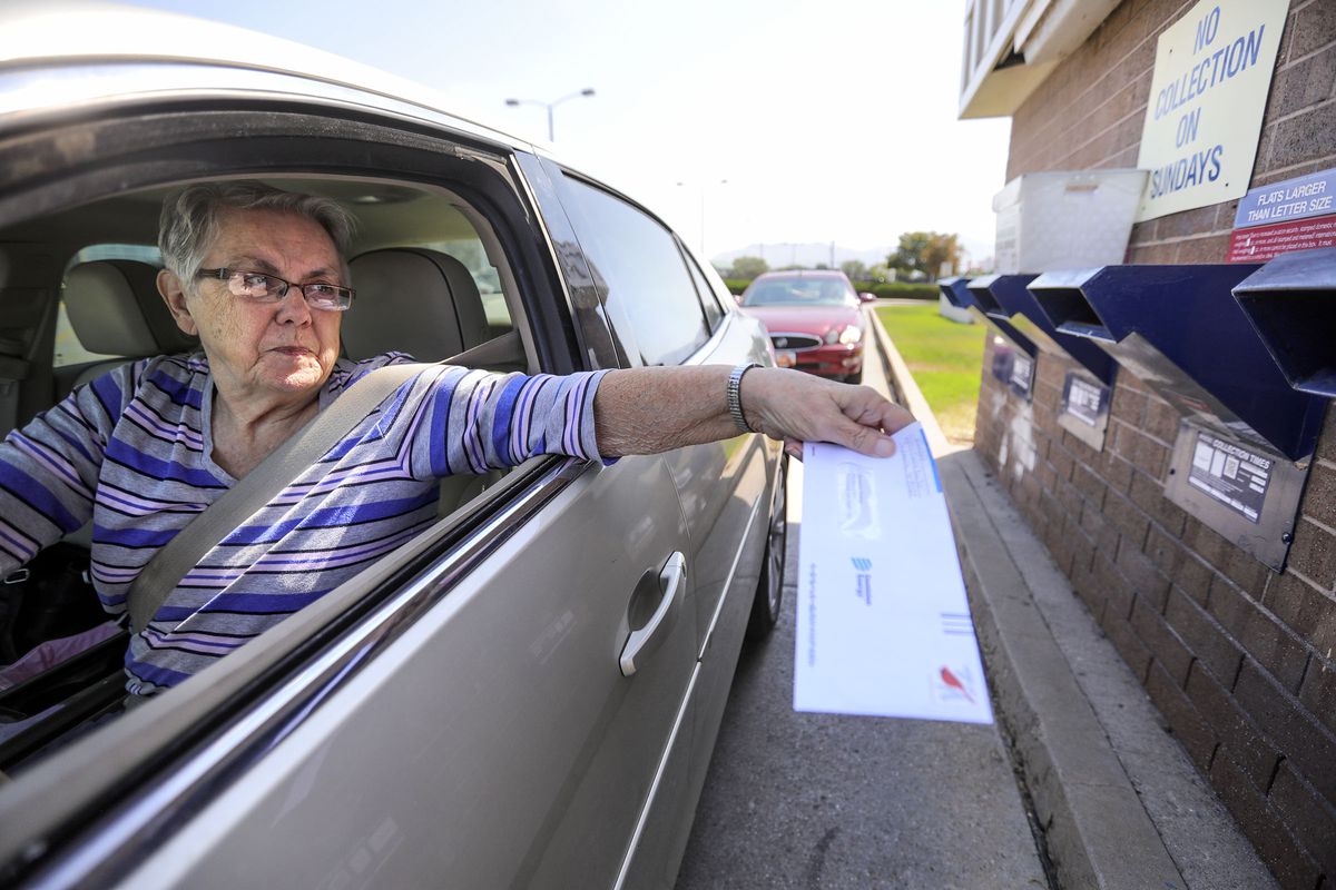 Barbara Monday drops off mail as another driver behind her waits to do the same at a U.S. Postal Service mail collection box in Salt Lake City on Tuesday, Aug. 18, 2020.