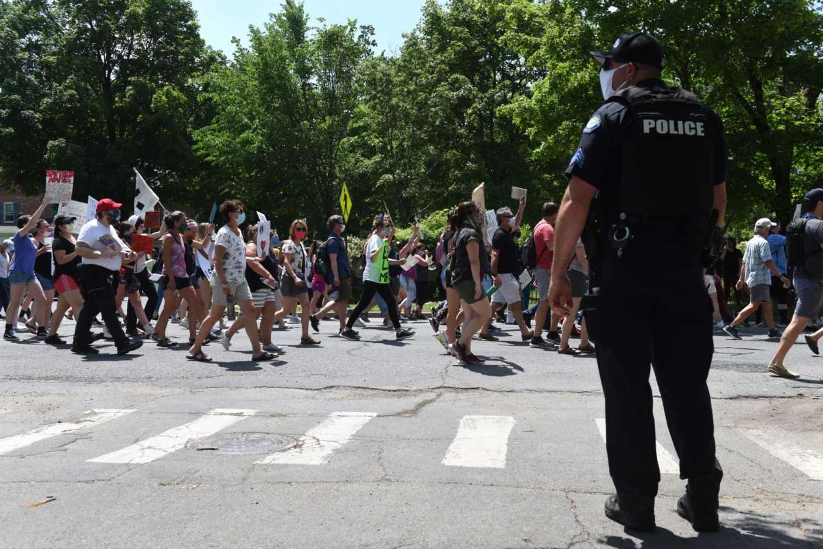 A police officer observes as protesters march down Glen Street during a Black Lives Matter rally on Friday, June 5, 2020, in Glens Falls, N.Y. (Will Waldron/Times Union)