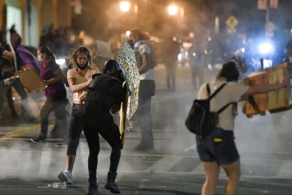 Protesters stand amid clouds of chemical irritant released by police outside the Public Safety Building in Rochester, N.Y., Thursday, Sept. 3, 2020. Seven police officers involved in the suffocation death of Daniel Prude in Rochester, New York, were suspended Thursday by the city's mayor, who said she was misled for months about the circumstances of the fatal encounter. (AP Photo/Adrian Kraus)